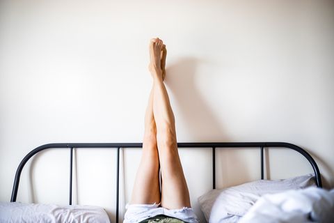 woman with legs raised wearing white shorts lying on bed