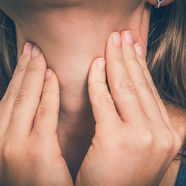 woman with throat sore is holding her aching throat