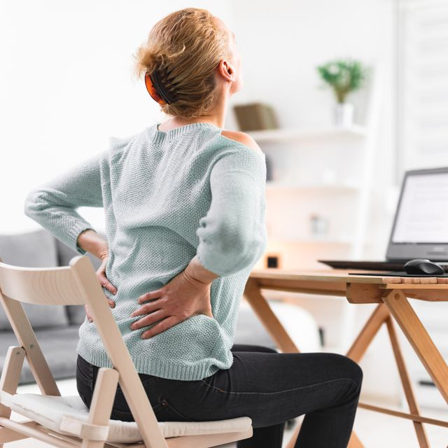 woman working on a laptop and having back, hip, spine pain