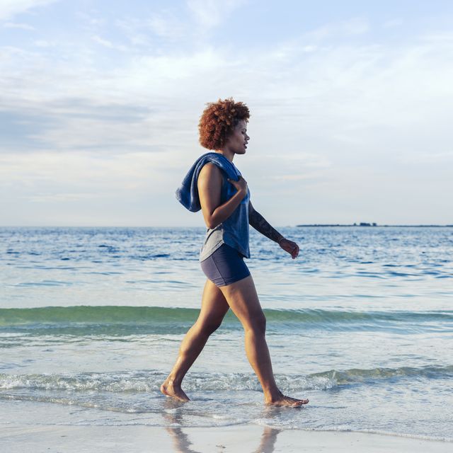 young female walking on a quiet beach barefoot
