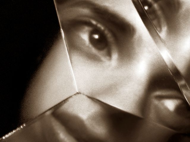 woman's face reflected in shards of broken glass