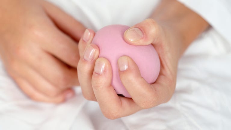 Woman's hand grasping a soft, pink ball, close-up