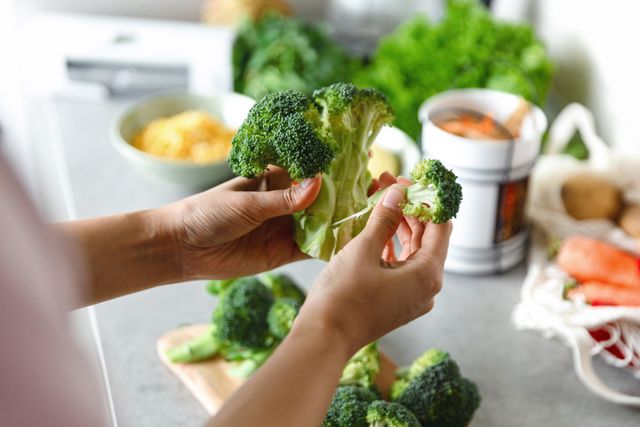 woman's hand peeling broccoli