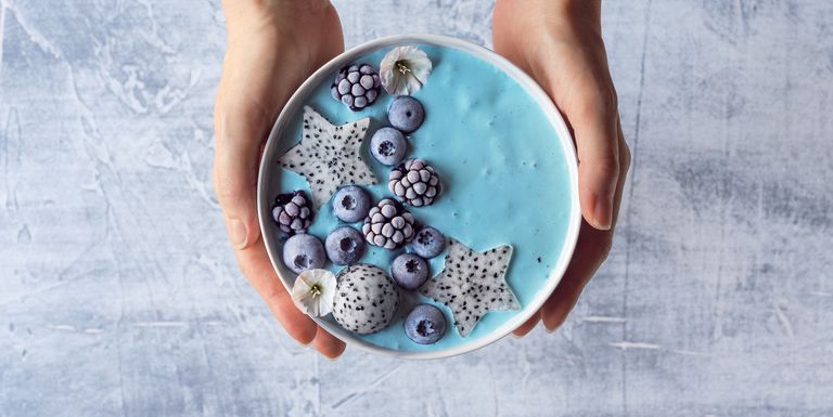 Woman's Hands Holding Blue Spirulina Yogurt Smoothie Bowl with Berries and Dragon Fruit