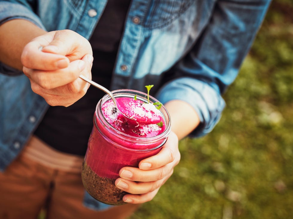 Woman's hands holding glass of rhubarb and chia seeds dessert with dark chocolate nibs