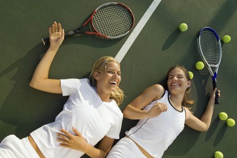 women fatigued and laughing after tennis match