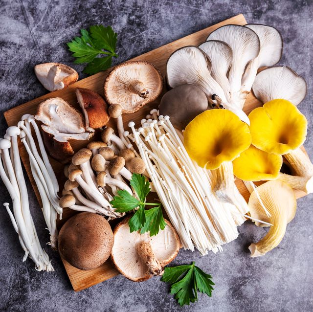 wooden table with variety of raw mushrooms