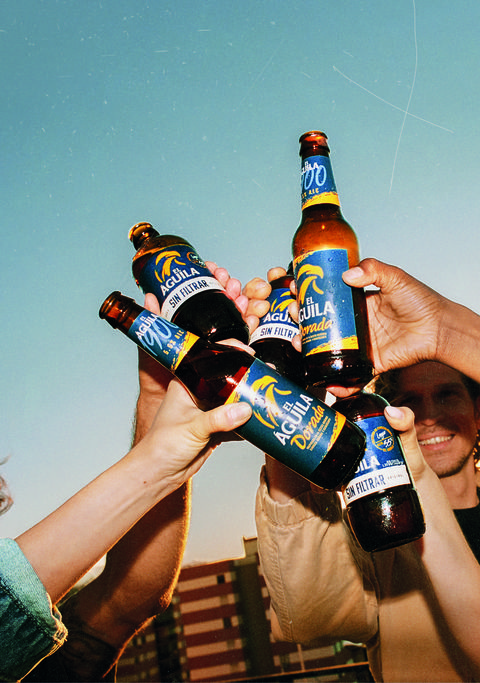 un grupo de personas brinda con cervezas el Águila