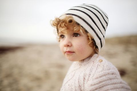 niña con jersey y gorro en la playa