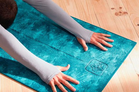 a person stretching on a blue yoga mat