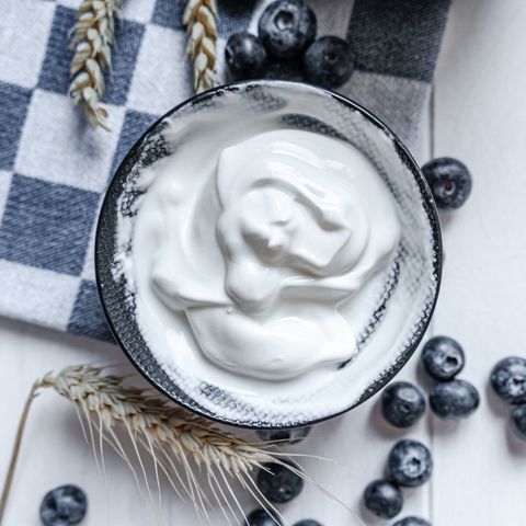 greek style yogurt in bowl on wooden table with blue and white napkin and blueberries