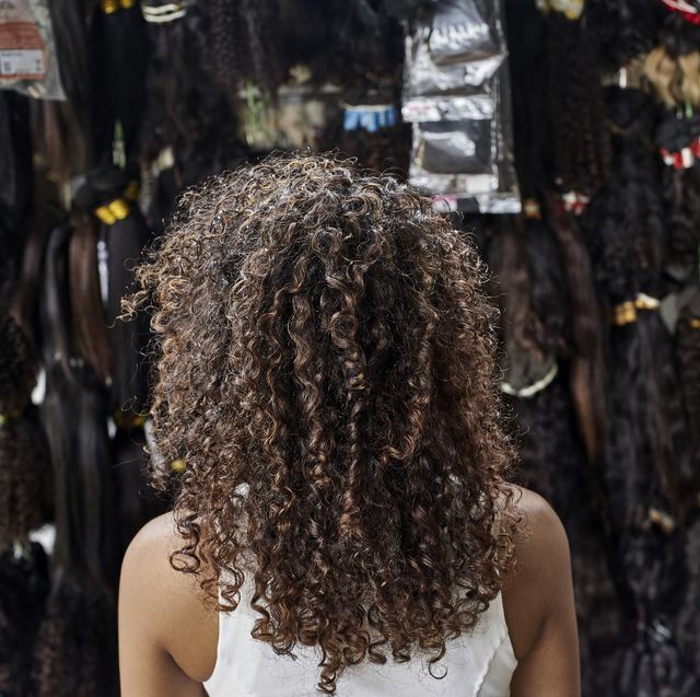 young african woman from behind with curly hair in a wig shop