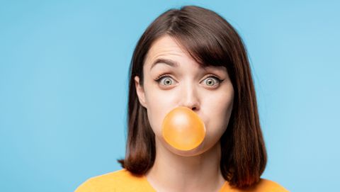 jonge vrouw blaast een grote bel met kauwgom