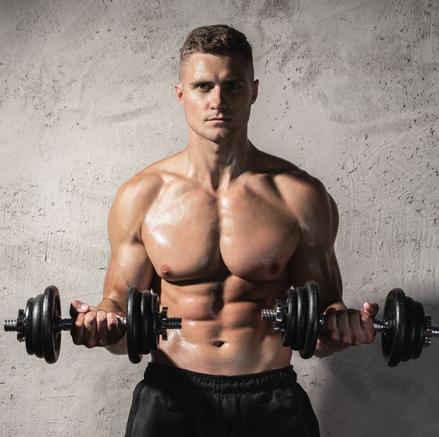 young and muscular bodybuilder man working out with dumbbells