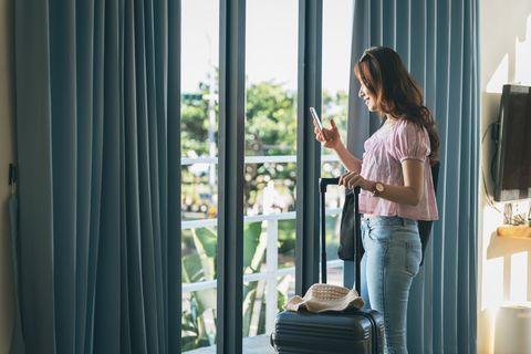 young asian female traveller by the window in a hotel room