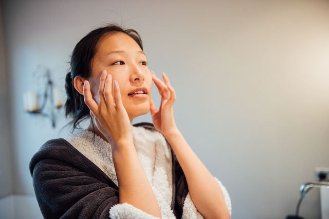 a young asian woman is washing her face