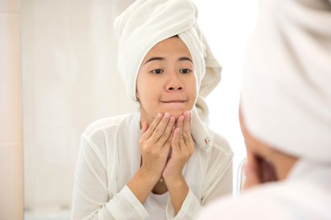 Young asian woman pressing her face, trying remove acne