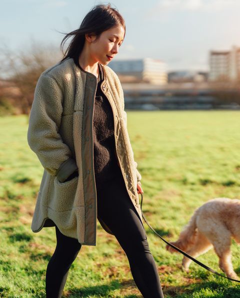 young asian woman walking her dog in the park on a sunny day