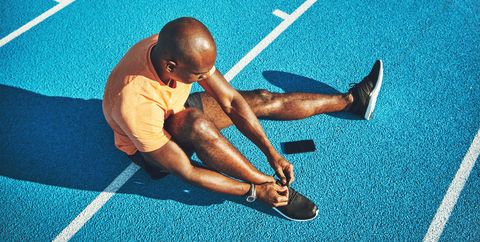 Young athlete tying up his shoes on a running track