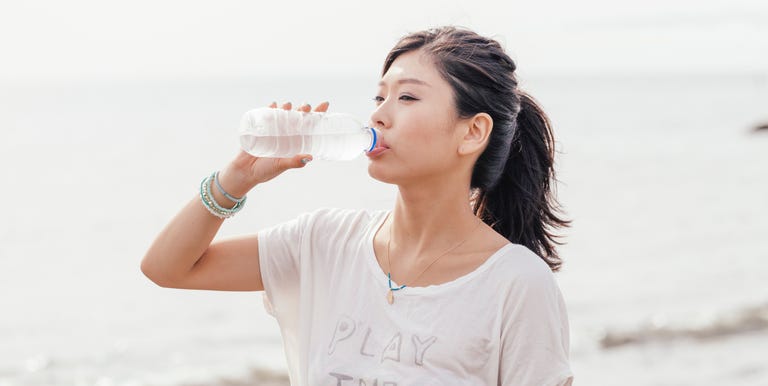 Young Athletic Asian Woman Drinking Water On The Beach