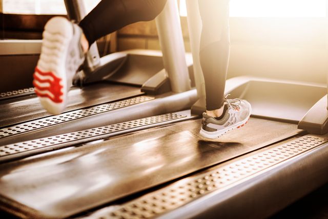 young athletic person running on treadmill legs close up