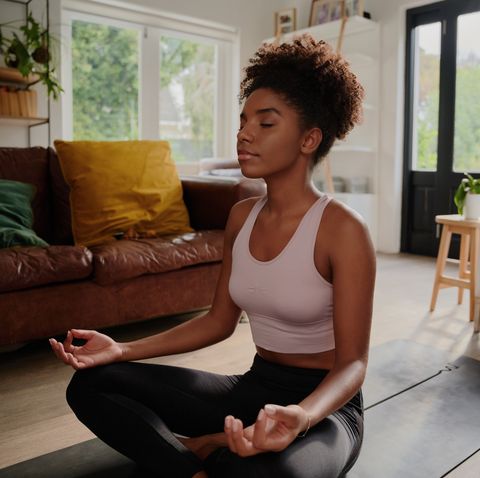 young black woman doing yoga at home in the lotus position