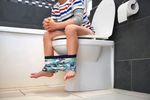 un niño pequeño, con una camiseta de rayas, con diarrea en el baño