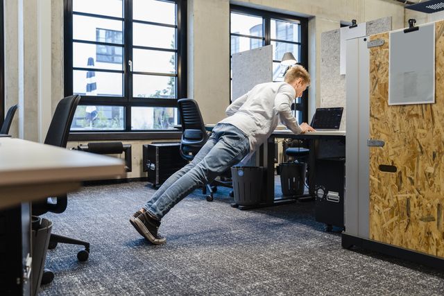 young businessman doing pushups at workplace