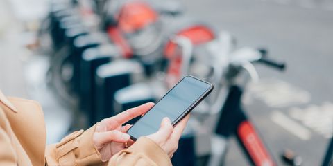 young businesswoman using phone to unlock a share bike in the city