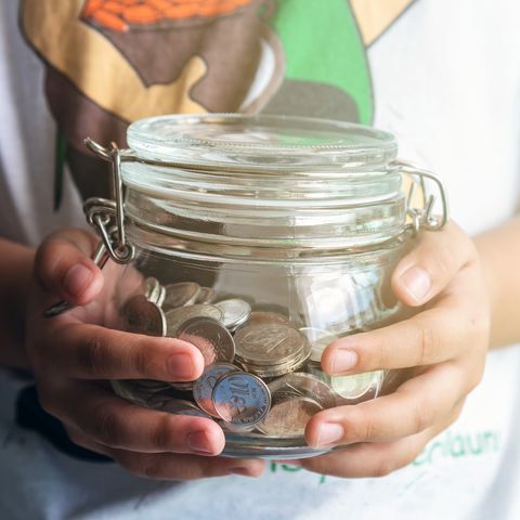 young child holding coins jar