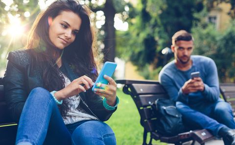 Young couple in the park texting on smartphones