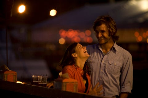 A young couple laughs and chats as they enjoy a beer on the deck of a local bar on the waterfront at Casco Bay Harbor in Portland, ME.