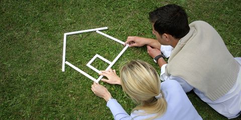 Young couple making house shape with rulers on grass