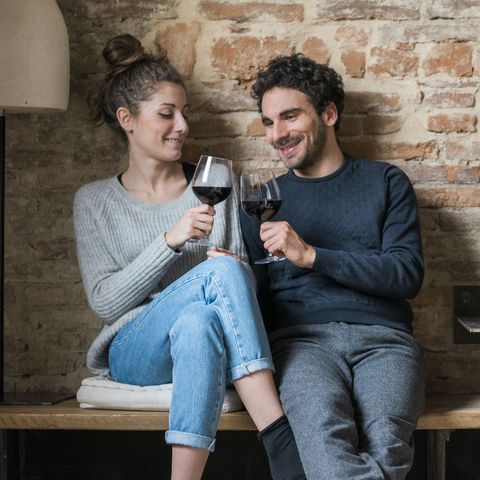 young couple raising a toast on kitchen bench