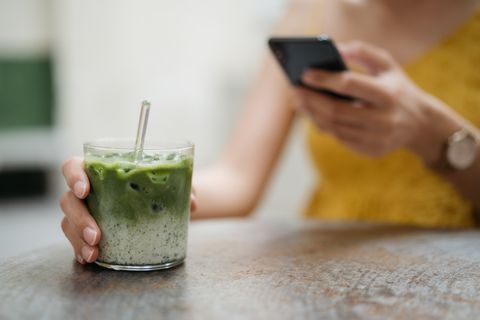 young female hand holding a glass of japanese ice matcha latte