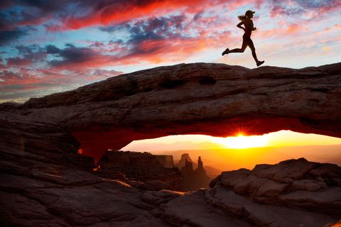 Young female runner running over rock formation at sunset, Moab, Utah, USA