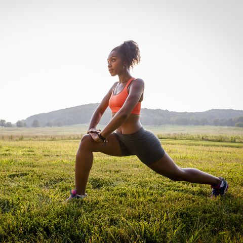 Young female runner stretching in rural park