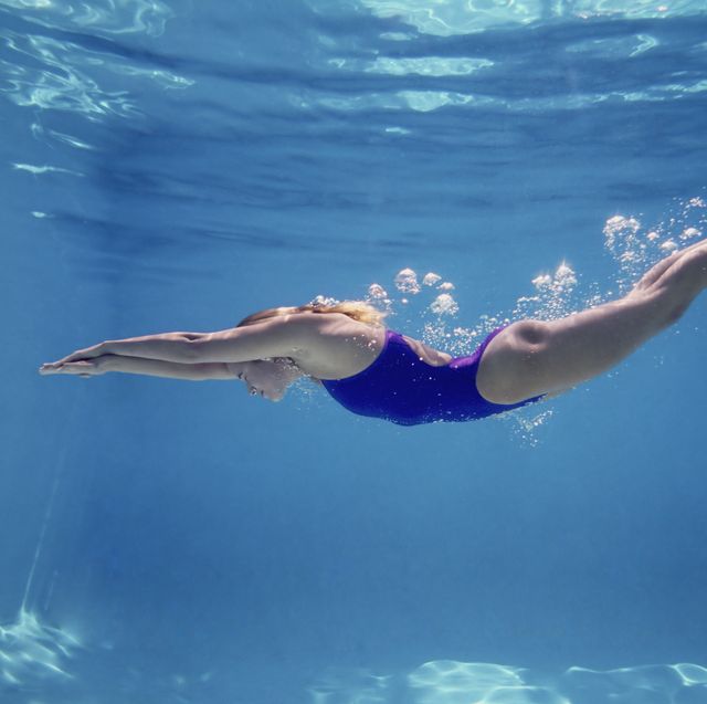 Young female swimming underwater, side view
