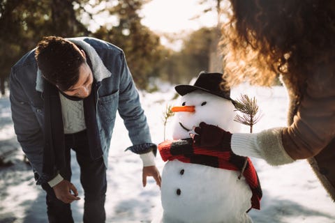 Young friends making snowman in the snow in winter Young friends making snowman in the snow in winter