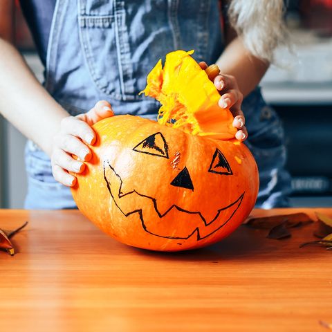 Young girl carving a pumpkin at Halloween