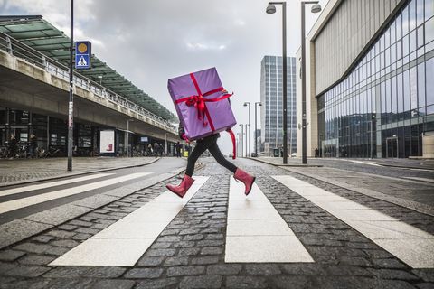 young girl running with large gift on street