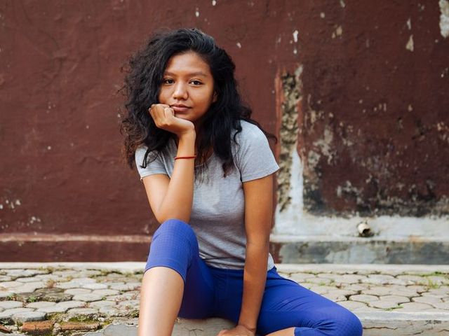 A young Indonesian woman with curly hair smiling