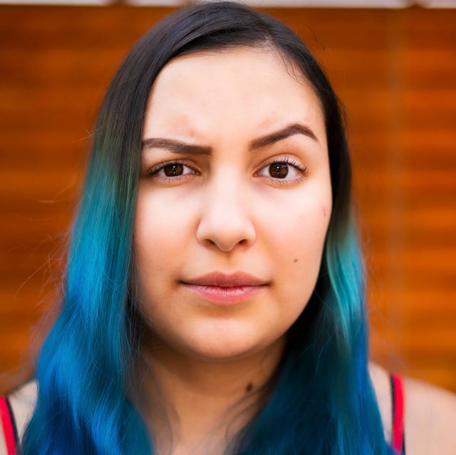 Young Latino woman with blue hair raising an eyebrow and looking at the camera young latino woman with blue hair raising an eyebrow and looking at the camera