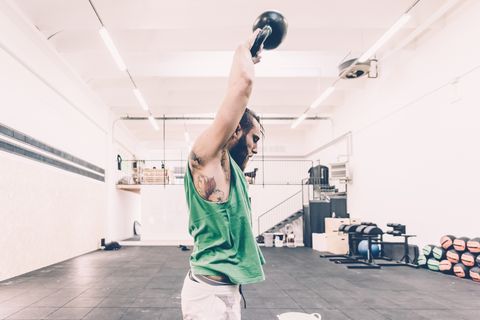 Young male cross trainer weightlifting kettlebell in gym