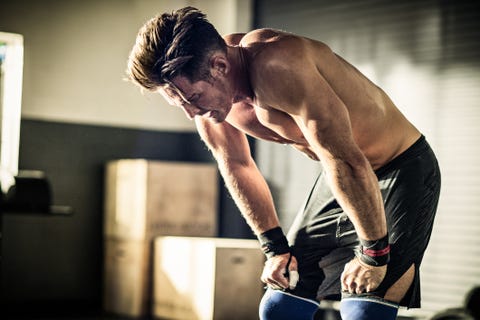 Young man bending forward with exhaustion in gymnasium