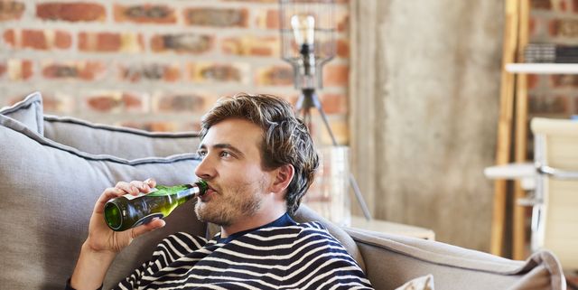 young man drinking beer while relaxing on sofa