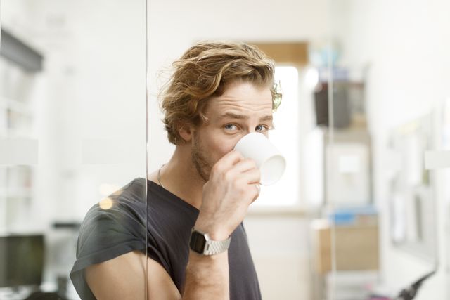 young man drinking coffee in office