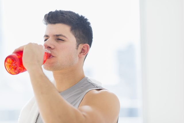 un hombre bebe una bebida energética rosa, que aumenta el rendimiento por afecto placebo