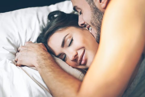 young man kissing girlfriend on bed