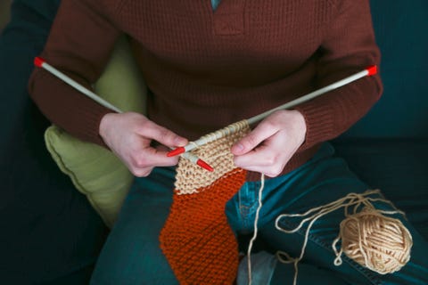 Young man knitting a scarf, partial view